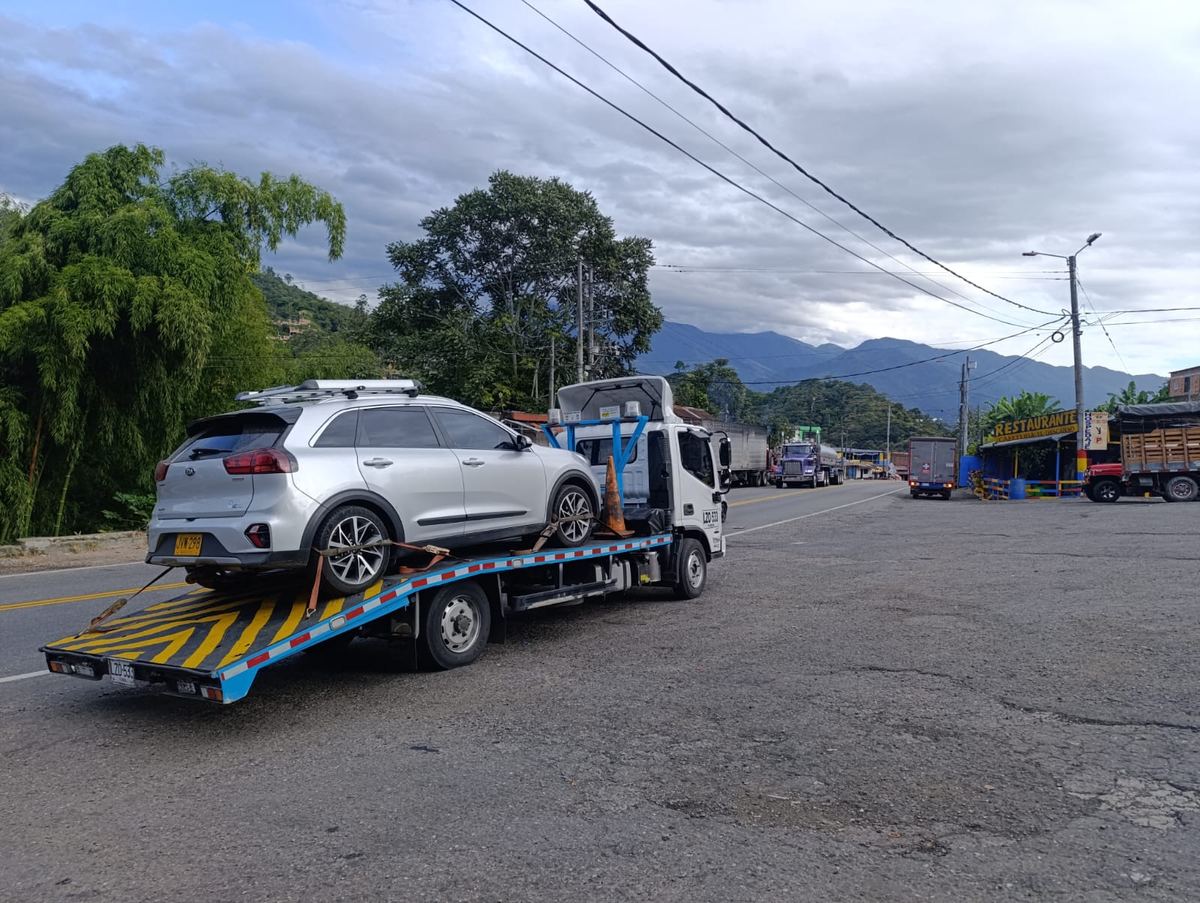 Automóvil transportado en grúa de plataforma por una carretera de montaña