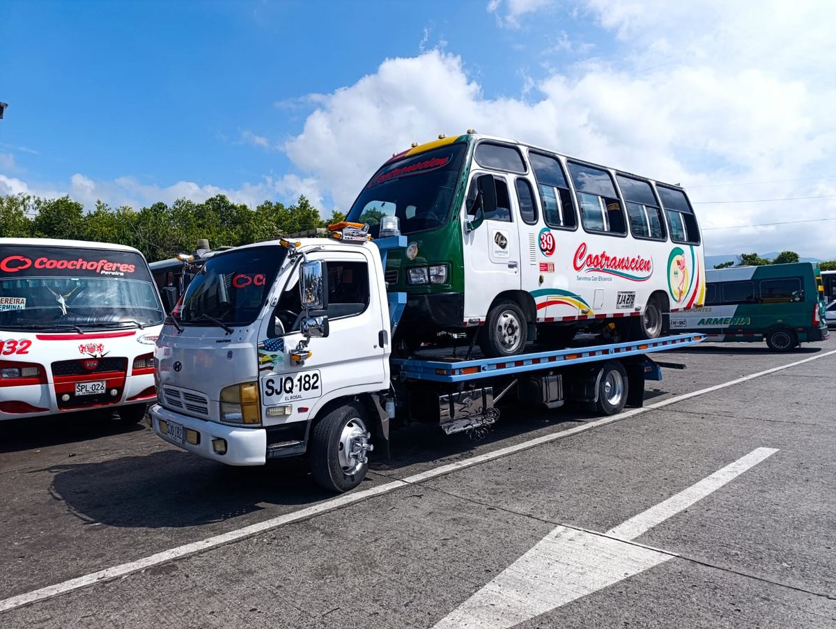 Buseta de servicio público sobre la grúa de plataforma de Servigrúas Armenia en el terminal de transportes