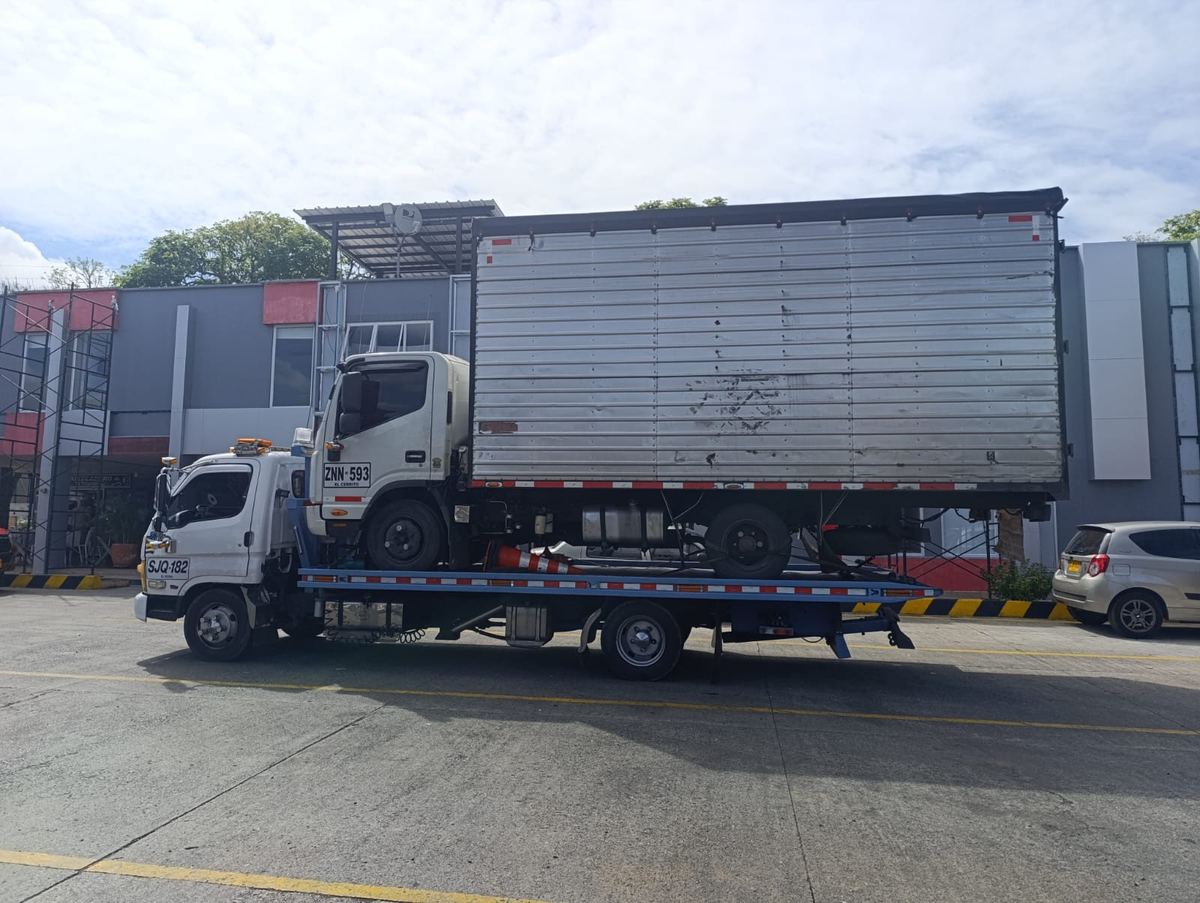 Camión furgón pequeño transportado sobre la grúa de plataforma de Servigrúas Armenia