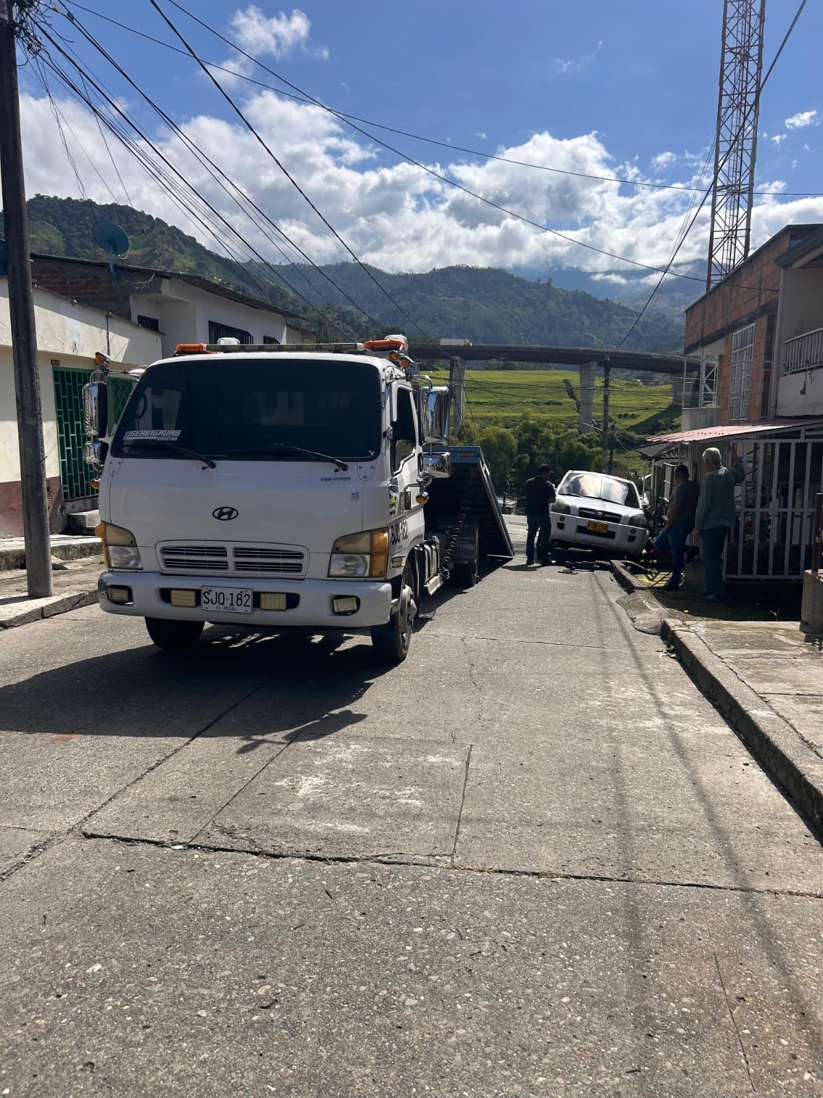 Grúa recogiendo un vehículo en una calle empinada de un municipio del Quindío